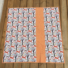 Load image into Gallery viewer, Canadian Diamond quilt pattern by Penny Spool Quilts, featuring four large diamonds surrounded by half-square triangles and a pieced border. Back of quilt shown featuring forest print with red and brown deer, with strip of orange fabric inserted off center.
