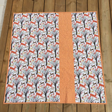 Load image into Gallery viewer, Canadian Diamond quilt pattern by Penny Spool Quilts, featuring four large diamonds surrounded by half-square triangles and a pieced border. Back of quilt shown featuring forest print with red and brown deer, with strip of orange fabric inserted off center.