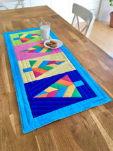 Load image into Gallery viewer, Festive Forest table runner and quilt block pattern by Penny Spool Quilts. Foundation paper pieced pattern. Image shows table runner in retro christmas colours of blue, orange, pink, green and yellow, on a table with glass of milk and cookies.