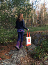 Load image into Gallery viewer, Young girl walking up a rocky path carrying a handmade quilted tote with the Popsicle block on it in yellow, orange and pink on white background, with orange handles and orange tote bottom. Popsicle 1 quilt block from the Ice Cream Sunday collection.