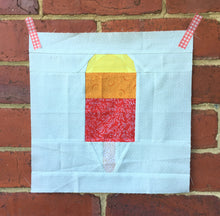 Load image into Gallery viewer, Popsicle 1 quilt block pattern by Penny Spool Quilts. Part of the Ice Cream Sunday collection. Tri-coloured popsicle in yellow, orange and red print fabrics on white background.