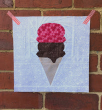 Load image into Gallery viewer, Ice Cream Cone quilt block pattern by Penny Spool Quilts. Part of the Ice Cream Sunday collection. Wafer cone with one scoop of chocolate ice cream and one scoop of pink ice cream, on white background. Shown on red brick wall
