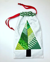 Load image into Gallery viewer, Festive Forest table runner and quilt block pattern by Penny Spool Quilts. Foundation paper pieced pattern. Image shows drawstring gift bag made from a single block in green on white, with red drawstring.
