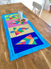 Load image into Gallery viewer, Festive Forest table runner and quilt block pattern by Penny Spool Quilts. Foundation paper pieced pattern. Image shows table runner in retro christmas colours of blue, orange, pink, green and yellow, on a table with glass of milk and cookies.

