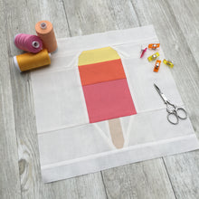 Load image into Gallery viewer, Popsicle 2 quilt block pattern by Penny Spool Quilts. Part of the Ice Cream Sunday collection. Tri-coloured popsicle with a bite taken out in top right corner, in yellow, orange and pink solid fabrics on white background. shown with spools of thread, clips and scissors

