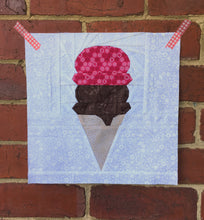 Load image into Gallery viewer, Ice Cream Cone quilt block pattern by Penny Spool Quilts. Part of the Ice Cream Sunday collection. Wafer cone with one scoop of chocolate ice cream and one scoop of pink ice cream, on white background. Shown on red brick wall
