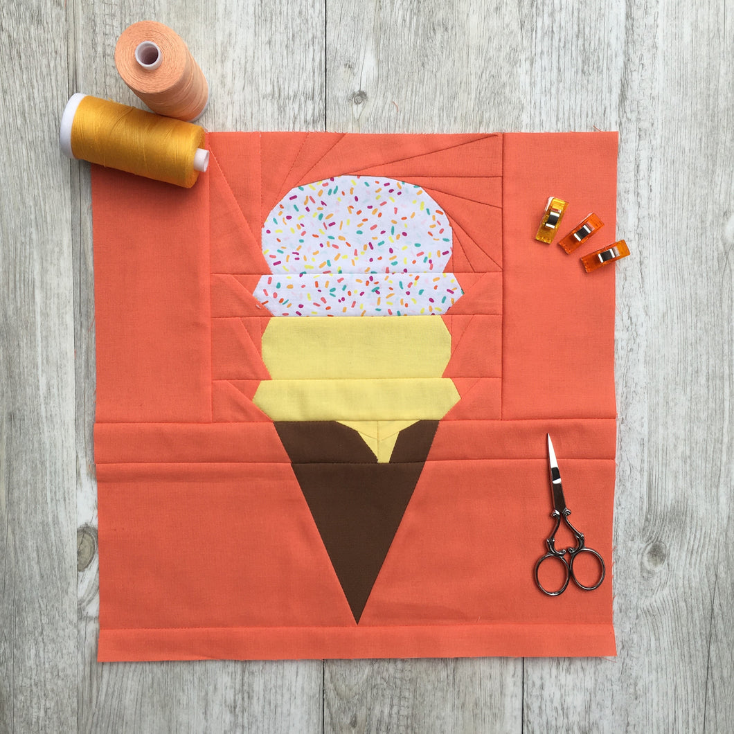 Ice Cream Cone quilt block pattern by Penny Spool Quilts. Part of the Ice Cream Sunday collection. Chocolate wafer cone with one scoop of yellow ice cream and one scoop of rainbow sprinkled ice cream, on orange background.